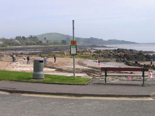 A bus stop without any shelter on a very open space over a slope and without any safety barrier